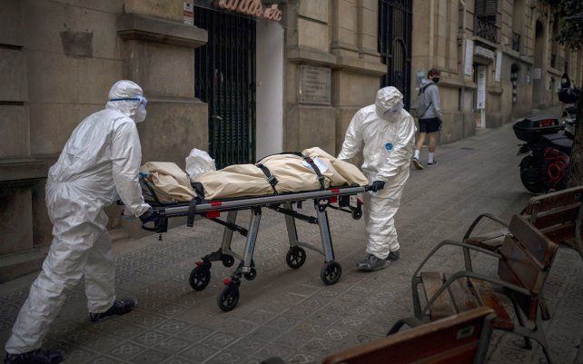 Los trabajadores de la morgue trasladan el cuerpo de una persona mayor que murió de COVID-19 después de sacarlo de un hogar de ancianos en Barcelona, España.