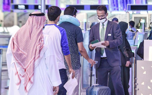 Un trabajador de la salud revisa la temperatura de pasajeros saudíes en el aeropuerto regional de Jizan