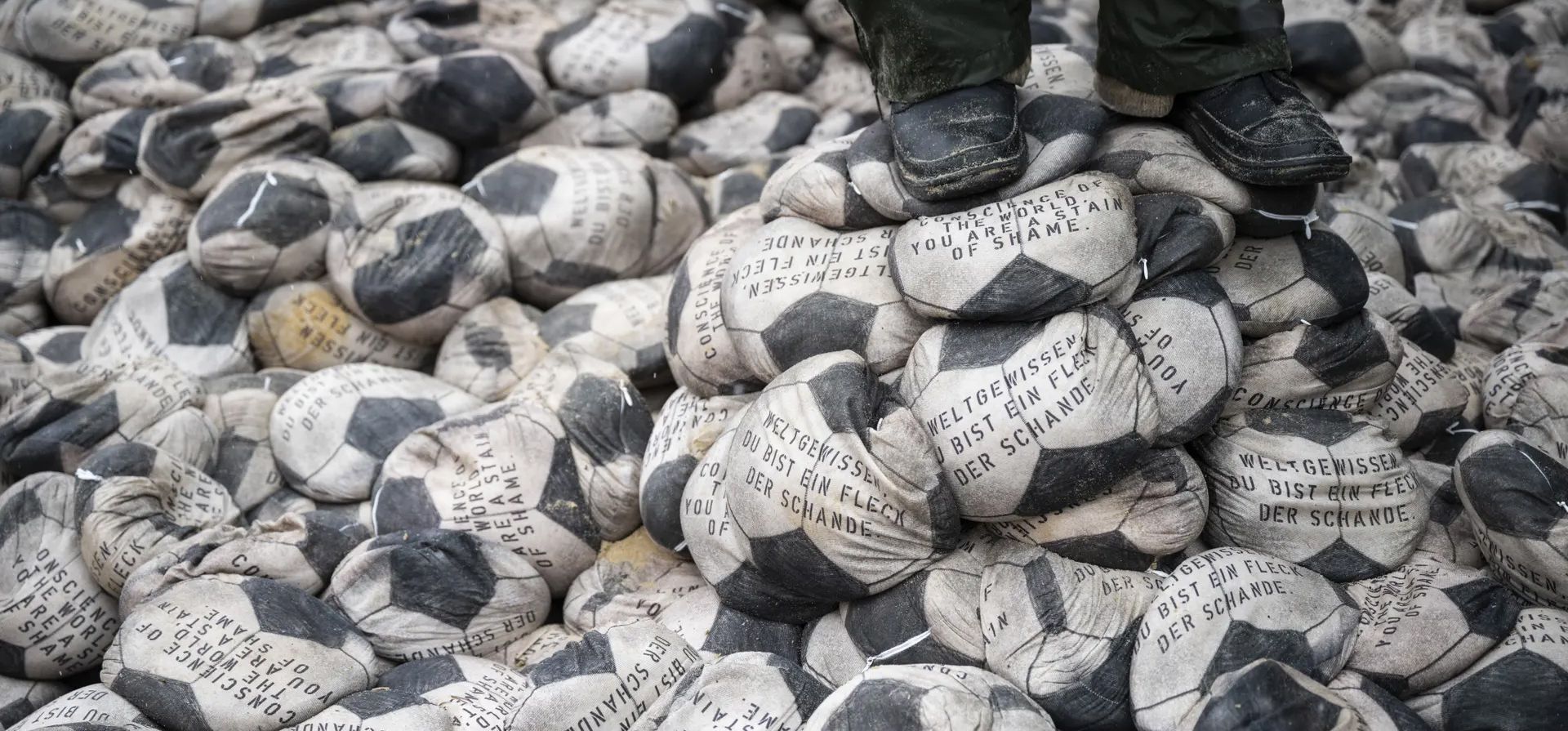 Una persona se para en algunos de los 6.500 pelotas de fútbol llenos de arena y colocados por el artista alemán Volker-Johannes Trieb frente a la sede de la FIFA. El mensaje