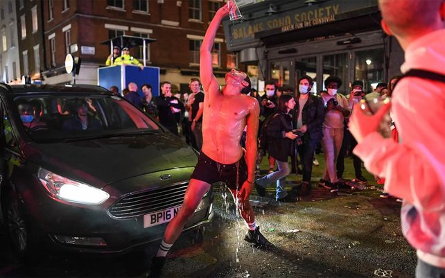 Un hombre se vierte agua sobre sí mismo en el Soho de Londres después de que se suavizaran las restricciones de cierre de pubs y restaurantes en Inglaterra. Fotografía: Peter Summers / Getty Images