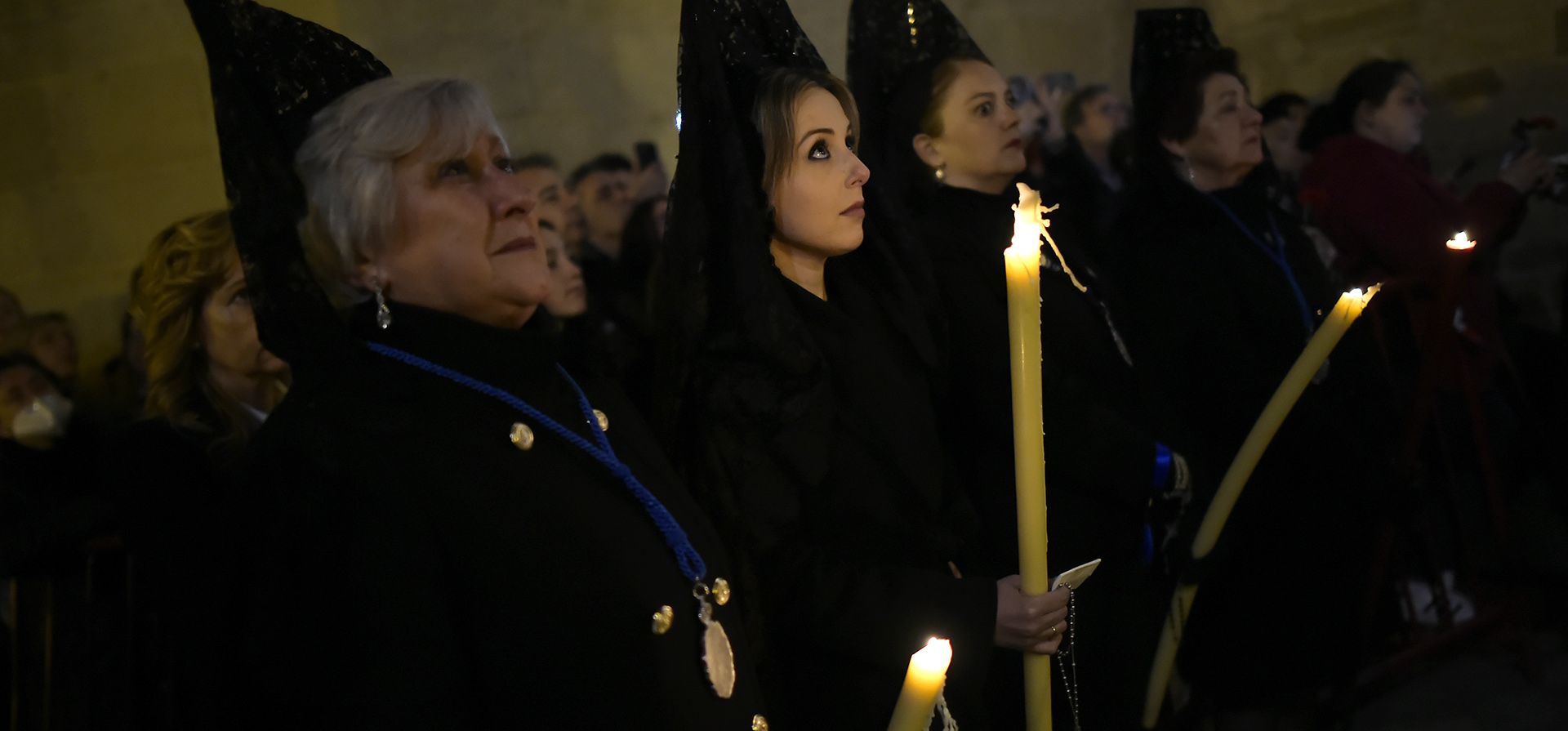 Devotos conocidos como "Las Manolas" encienden velas mientras participan en la procesión del Lunes Santo en Logroño, norte de España, el lunes 3 de abril de 2023. (Foto AP/Álvaro Barrientos)