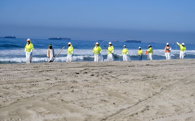 Trabajadores limpian la playa contaminada después de un derrame de petróleo en Huntington Beach, California. La Guardia Costera recibió el primer informe de un posible derrame de petróleo frente a la costa del sur de California.