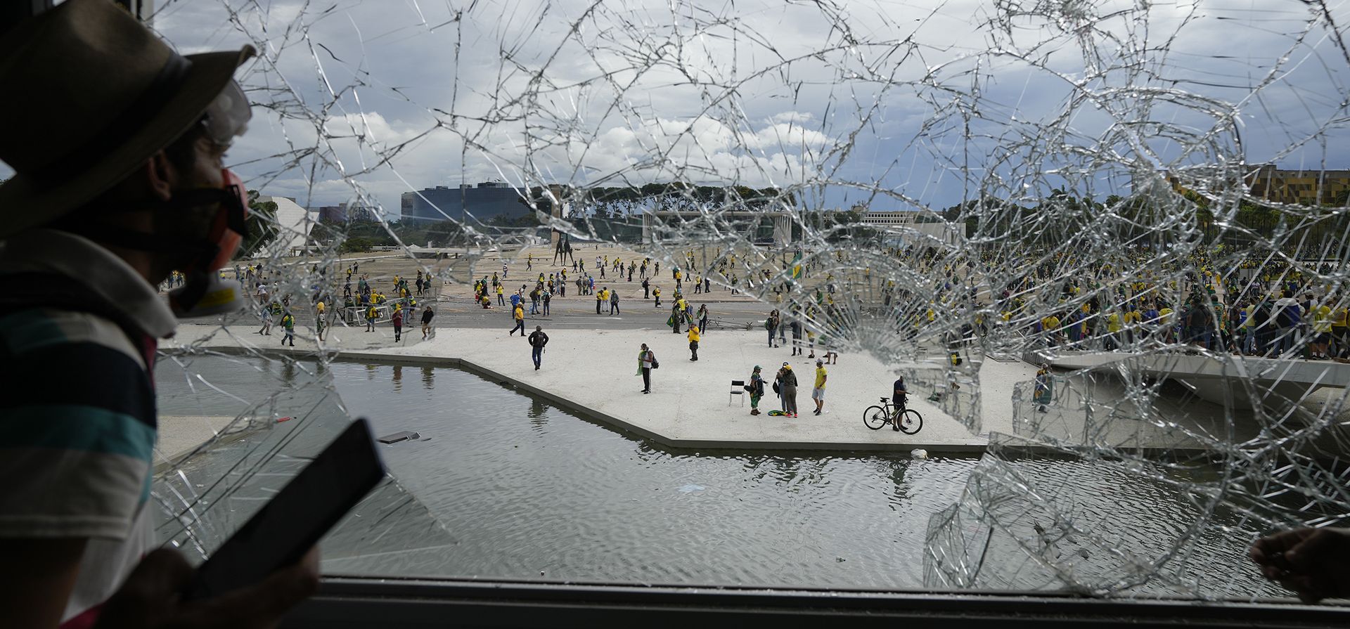 Un manifestante, partidario del expresidente brasileño Jair Bolsonaro, mira desde una ventana rota del Palacio de Planalto después de que él y muchos otros lo asaltaron, en Brasilia, Brasil, el domingo 8 de enero de 2023. Planalto es el lugar de trabajo oficial del presidente de Brasil. (Foto AP/Eraldo Peres)