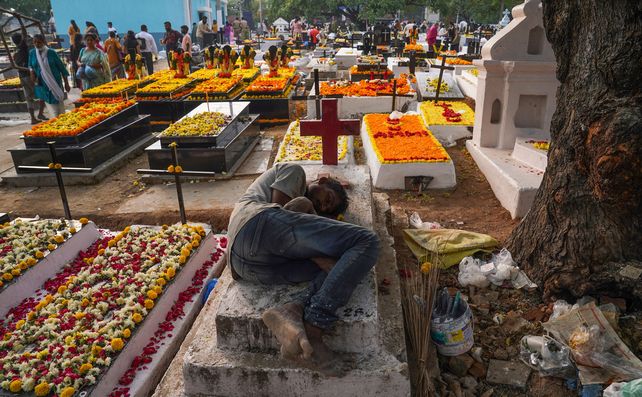 En Hyderabad (India) un trabajador reposa en una tumba&nbsp; mientras sus familiares se reúnen con velas y flores para ofrecer oraciones por las almas difuntas.