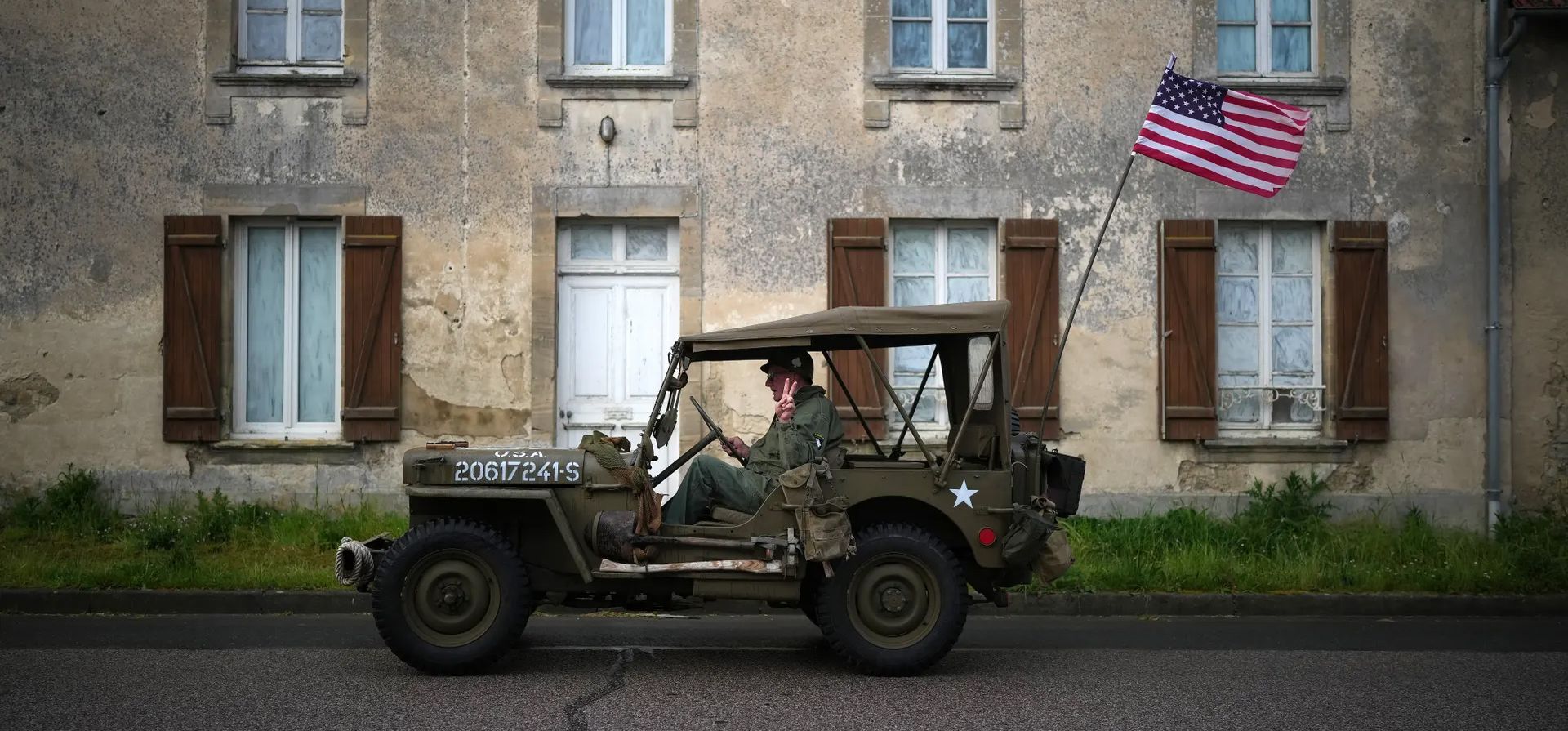 Un hombre hace una señal de victoria mientras conduce un jeep estadounidense de la Segunda Guerra Mundial a través de un tranquilo pueblo de Normandía antes del 80 aniversario del desembarco del Día D, Colleville-sur-Mer, Francia. Fotografía: Christopher Furlong/Getty Images Un hombre hace una señal de victoria mientras conduce un jeep estadounidense de la Segunda Guerra Mundial a través de un tranquilo pueblo de Normandía antes del 80 aniversario del desembarco del Día D, Colleville-sur-Mer, Francia. Fotografía: Christopher Furlong/Getty Images
