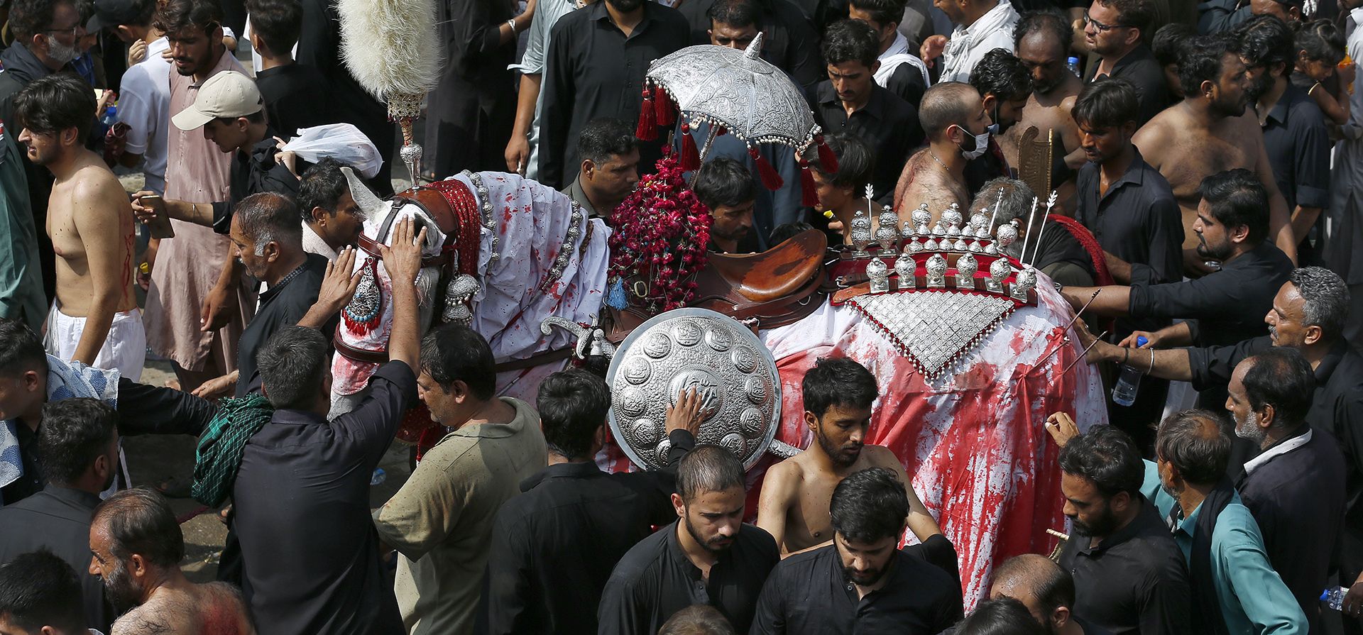 Musulmanes chiítas tocan un caballo, que simboliza el caballo que llevó al Imam Hussein durante la batalla de Karbala, durante una procesión para conmemorar Ashura, en Rawalpindi, Pakistán, el martes 9 de agosto de 2022.