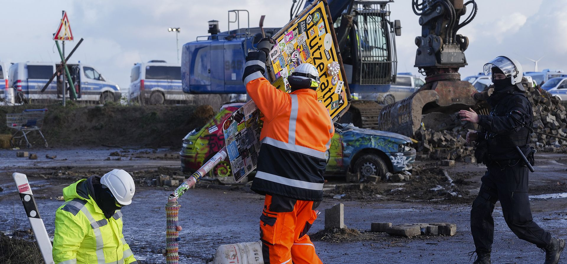 Con la ayuda de un oficial de policía, los trabajadores de la compañía energética alemana RWE derribaron el letrero del lugar en la aldea Luetzerath cerca de Erkelenz, Alemania, el miércoles 11 de enero de 2023. (Foto AP/Michael Probst)