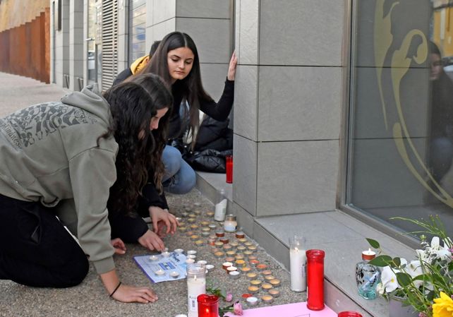 Adolescentes rinden homenaje en el altar levantado frente al edificio.