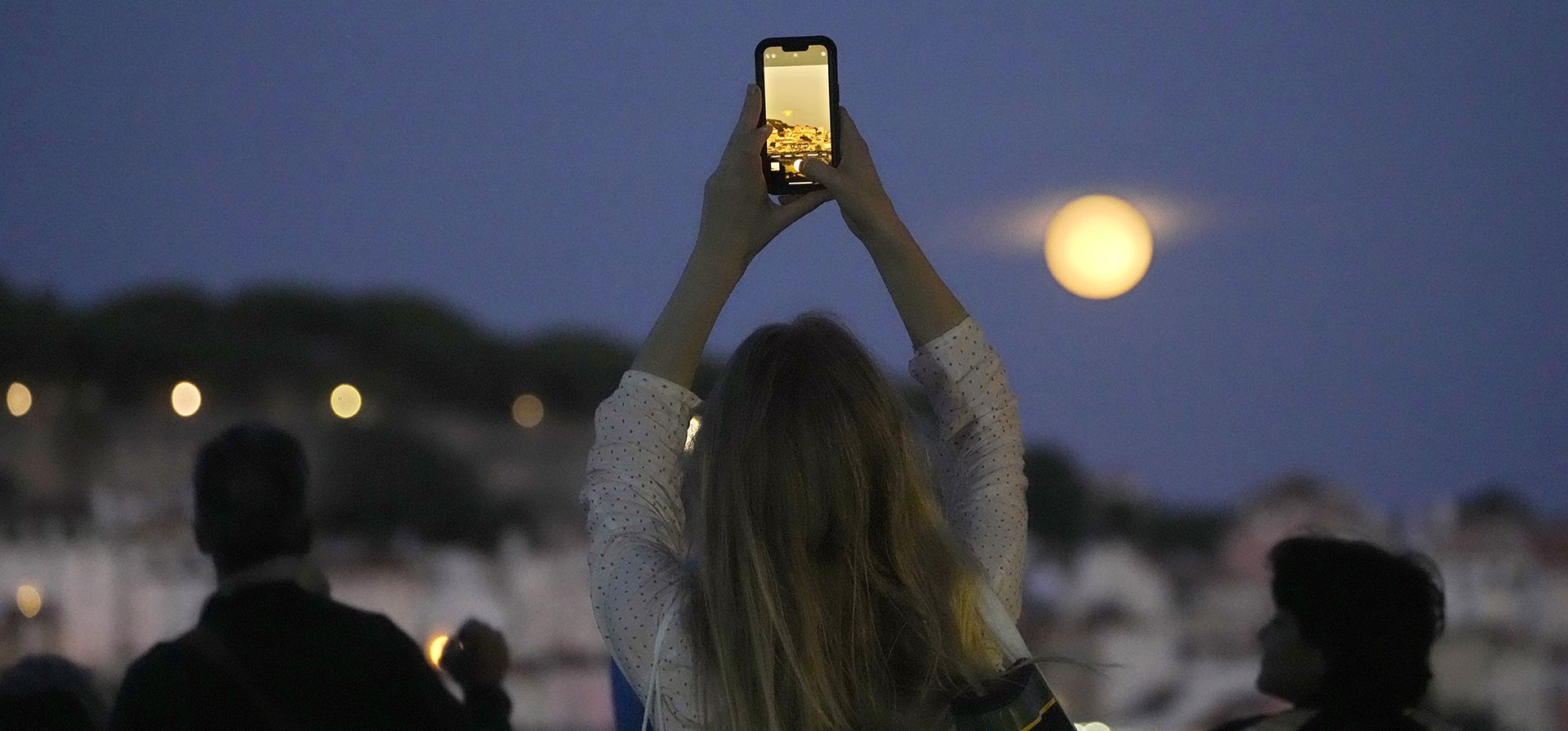 Una mujer toma fotografías de una superluna que se eleva sobre Lisboa, el miércoles 30 de agosto de 2023. (Foto AP/Armando Franca)