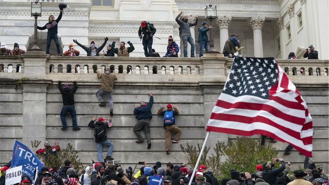 Manifestantes escalan un muro en el Capitolio de los Estados Unidos el 6 de enero de 2021 en Washington. Muchos están siendo juzgados y condenados. Trump prometió indultarlos.