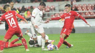 Pablo Pérez traslada el balón entre Elizalde y Sarrafiore. El volante cumplió en su retorno a la titularidad.