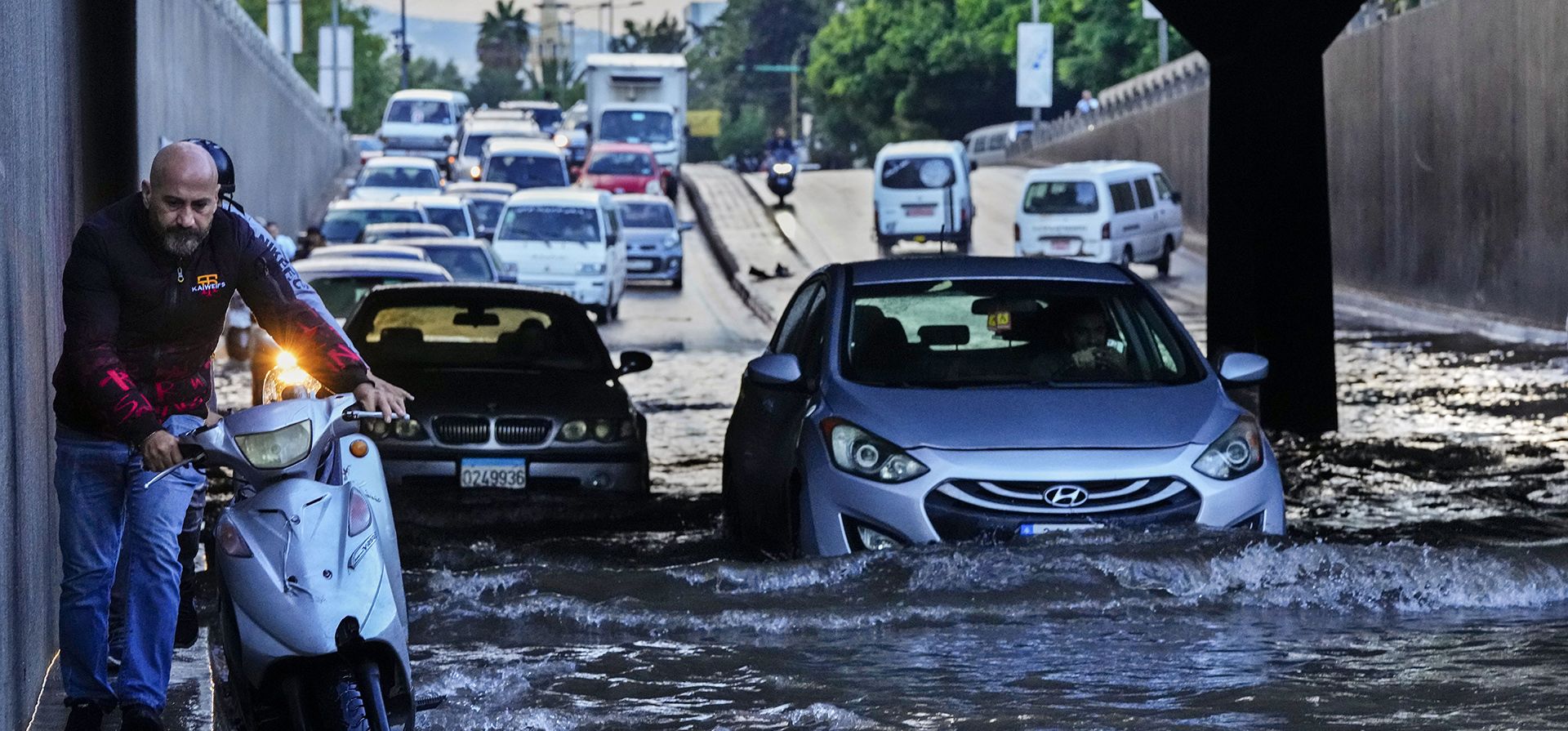 Un hombre empuja su motocicleta mientras los autos circulan por una carretera inundada después de que cayera una fuerte lluvia temprano en la mañana en Beirut, Líbano, el miércoles 4 de octubre de 2023. (Foto AP/Hassan Ammar) Un hombre empuja su motocicleta mientras los autos circulan por una carretera inundada después de que cayera una fuerte lluvia temprano en la mañana en Beirut, Líbano, el miércoles 4 de octubre de 2023. (Foto AP/Hassan Ammar)