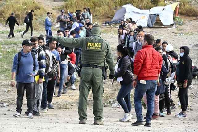 Un policía estadounidense de fronteras dirige a un grupo de inmigrantes en la zona de San Diego, California.