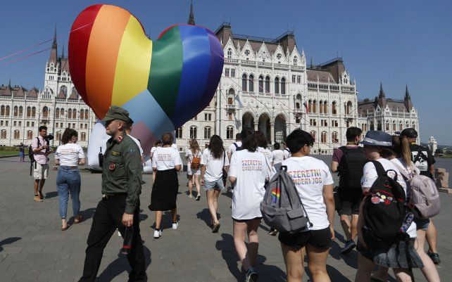 Activistas pasan junto a un gran corazón de colores del arco iris erigido frente al edificio del parlamento del país en Budapest, Hungría. Los activistas protestan contra la ley recientemente aprobada que, según ellos, discrimina y margina a las personas LGBTQ+I.