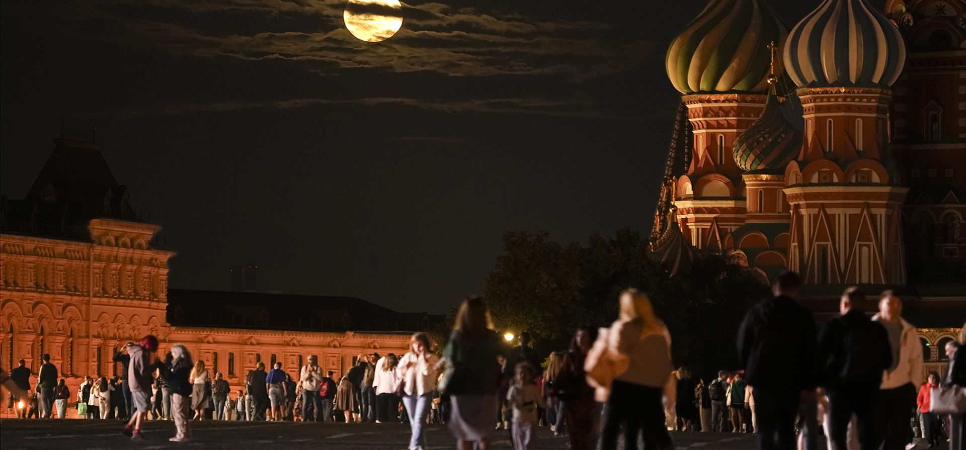La Súper Luna Azul de agosto se ubica detrás de un edificio histórico y la Catedral de San Basilio, mientras la gente camina en la Plaza Roja en Moscú, Rusia, el miércoles 30 de agosto de 2023. (Foto AP/Alexander Zemlianichenko)