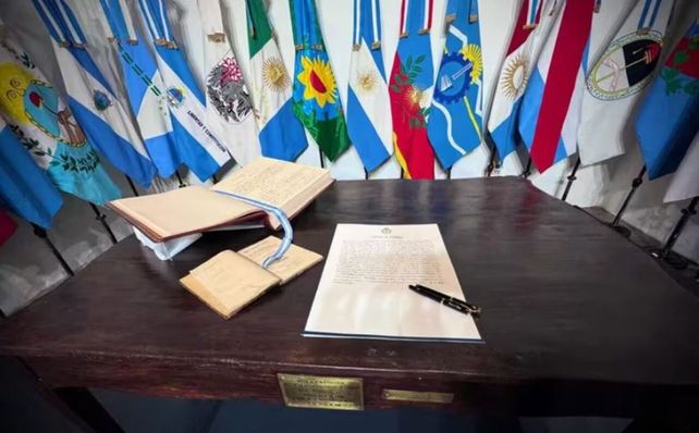El acta acuerdo junto a las banderas de las provincias que participaron de la rúbrica.