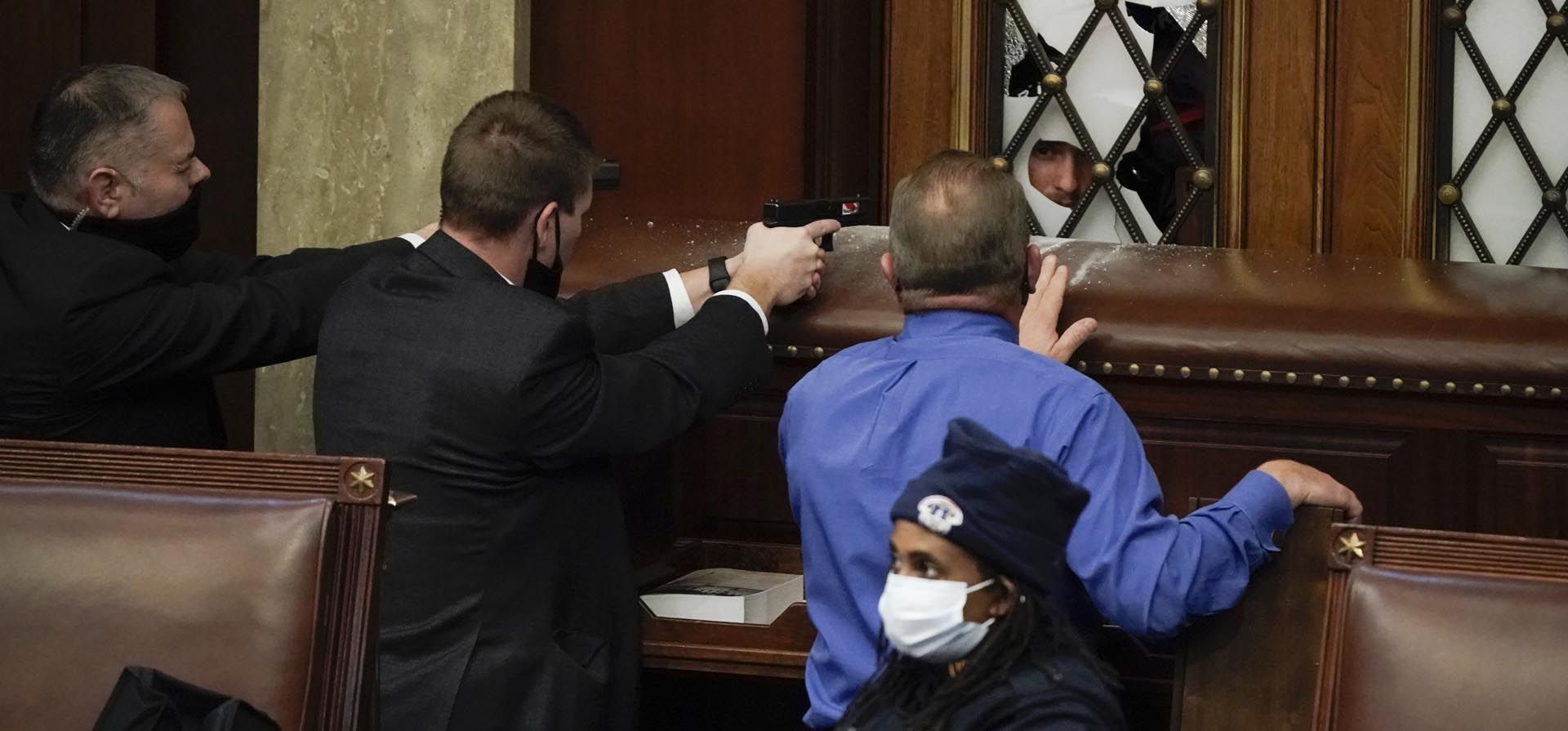 Agentes de seguridad apuntan con sus armas a los manifestantes que intentan irrumpir en la Cámara del Capitolio de los Estados Unidos el 6 de enero de 2021 en Washington.