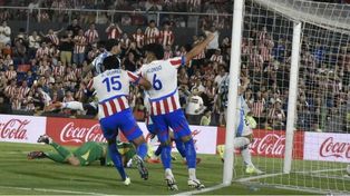 Los futbolistas de Paraguay celebran el tanto guaraní, mientras el Dibu Martínez intenta pero no puede.