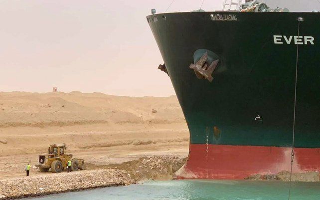 Una excavadora intenta liberar el extremo delantero del buque portacontenedores Ever Given, operado por Evergreen Marine, después de que encalló en el extremo sur del Canal de Suez, bloqueando el tráfico de navegación en ambas direcciones.