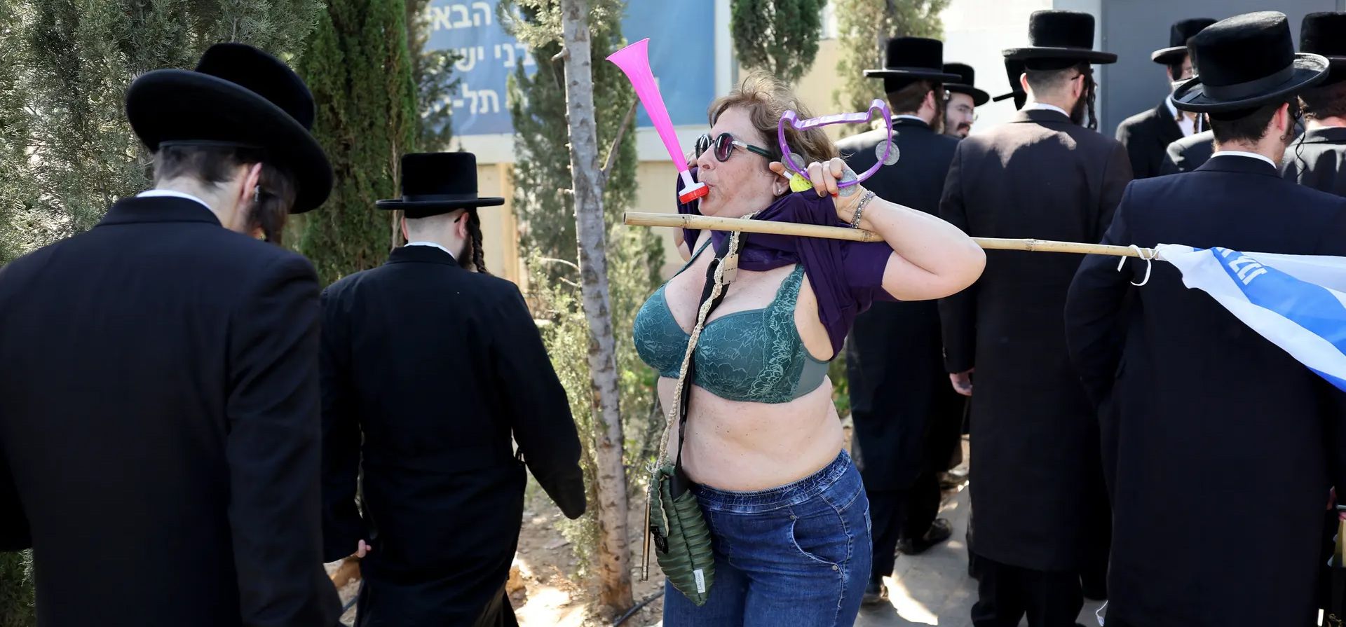 Una manifestante levanta su camiseta junto a hombres ultraortodoxos frente a una oficina de reclutamiento del ejército en la ciudad de Kiryat Ono, cerca de Tel Aviv, durante una manifestación contra su exención de servir en el ejército, Kiryat Ono, Israel . Fotografía: Jack Guez/AFP/Getty Images Una manifestante levanta su camiseta junto a hombres ultraortodoxos frente a una oficina de reclutamiento del ejército en la ciudad de Kiryat Ono, cerca de Tel Aviv, durante una manifestación contra su exención de servir en el ejército, Kiryat Ono, Israel . Fotografía: Jack Guez/AFP/Getty Images
