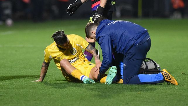Damián Martínez ya recibió el golpe en la rodilla izquierda y es atendido por los auxiliares canallas. Tuvo que dejar la cancha.