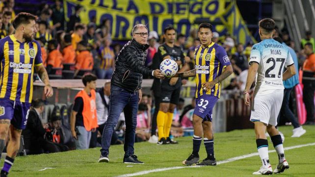 Ariel Holan le alcanza la pelota a Emanuel Coronel