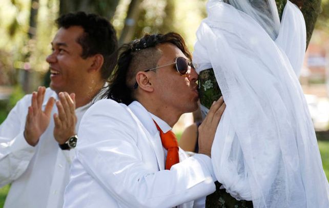 El novio lució un impecable traje blanco y corbata roja. El árbol un lazo blanco.