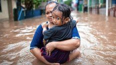 Una mujer carga a su hija tratando de ponerse a salvo durante las inundaciones en Yakarta, Indonesia