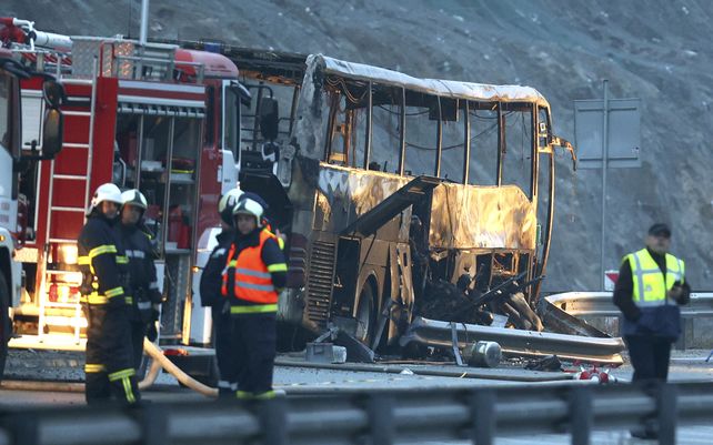 Bomberos y trabajadores forenses inspeccionan la escena de un accidente de autobús que