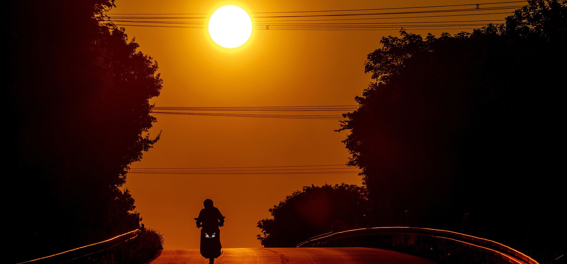 Un hombre monta su scooter sobre una colina en las afueras de Frankfurt, Alemania, durante el amanecer del lunes 9 de mayo de 2022.
