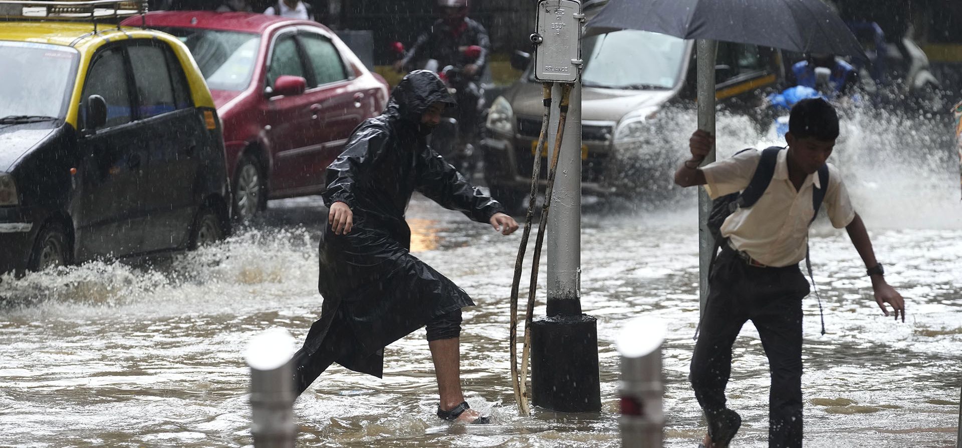 La gente atraviesa una calle anegada durante las fuertes lluvias en Mumbai, India, el martes 5 de julio de 2022.