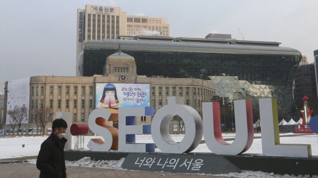 Un hombre camina frente al logotipo de la ciudad capital de Corea del Sur.