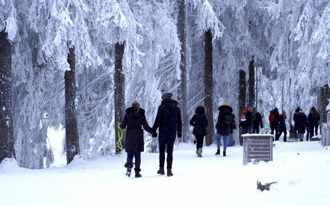 Turistas recorren un sendero nevado en el bosque negro cerca del lago Mummelsee, Alemania.