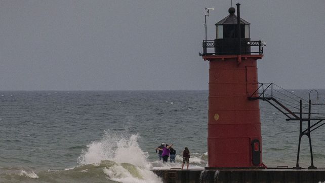 Turistas son golpeadas por una ola mientras se encuentran al final del muelle de South Haven en South Haven