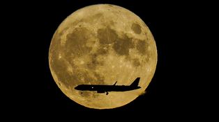 Una superluna, también llamada luna del esturión, se eleva cuando un avión de pasajeros se acerca al aeropuerto internacional John F. Kennedy, madrugada 12 de agosto de 2022, en Nueva York. (Foto AP/Bebeto Matthews)