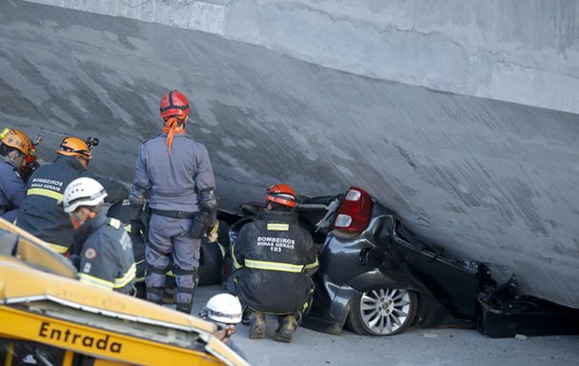 Espantoso. Un bombero trata de rescatar el cuerpo del ocupante de un auto aplastado por la mole de cemento.