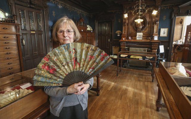 Anne Hoguet, directora del museo de fabricación de abanicos posa con un abanico de madera asado que representa la caza del halcón, pintura gouache sobre papel de 1880 en París.