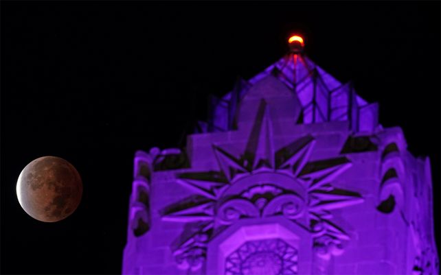 La sombra de la tierra cubre la luna llena durante un eclipse lunar parcial cuando se pone más allá de un edificio de apartamentos