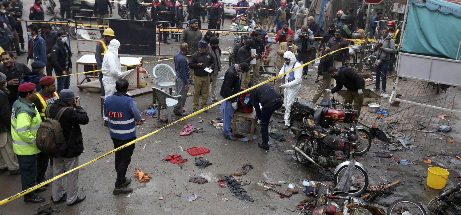 Oficiales de policía examinan el lugar de la explosión de una bomba en Lahore, Pakistán, el jueves 20 de enero de 2022. La policía dijo que la poderosa bomba explotó en un bazar lleno de gente en Lahore, la segunda ciudad más grande de Pakistán, matando a varias personas e hiriendo a decenas.