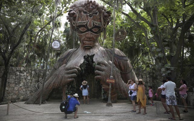 Turistas esperan turno para posar con una escultura figurativa que sirve como arco del artista sudafricano Daniel Popper titulada