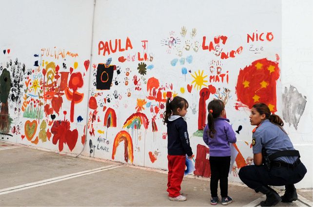 Agentes de la Policía Comunitaria junto a chicos y vecinos realizando el mural.