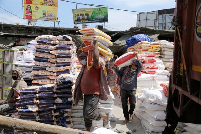 Trabajadores transportan bolsas de granos alimenticios en un almacén en Jammu