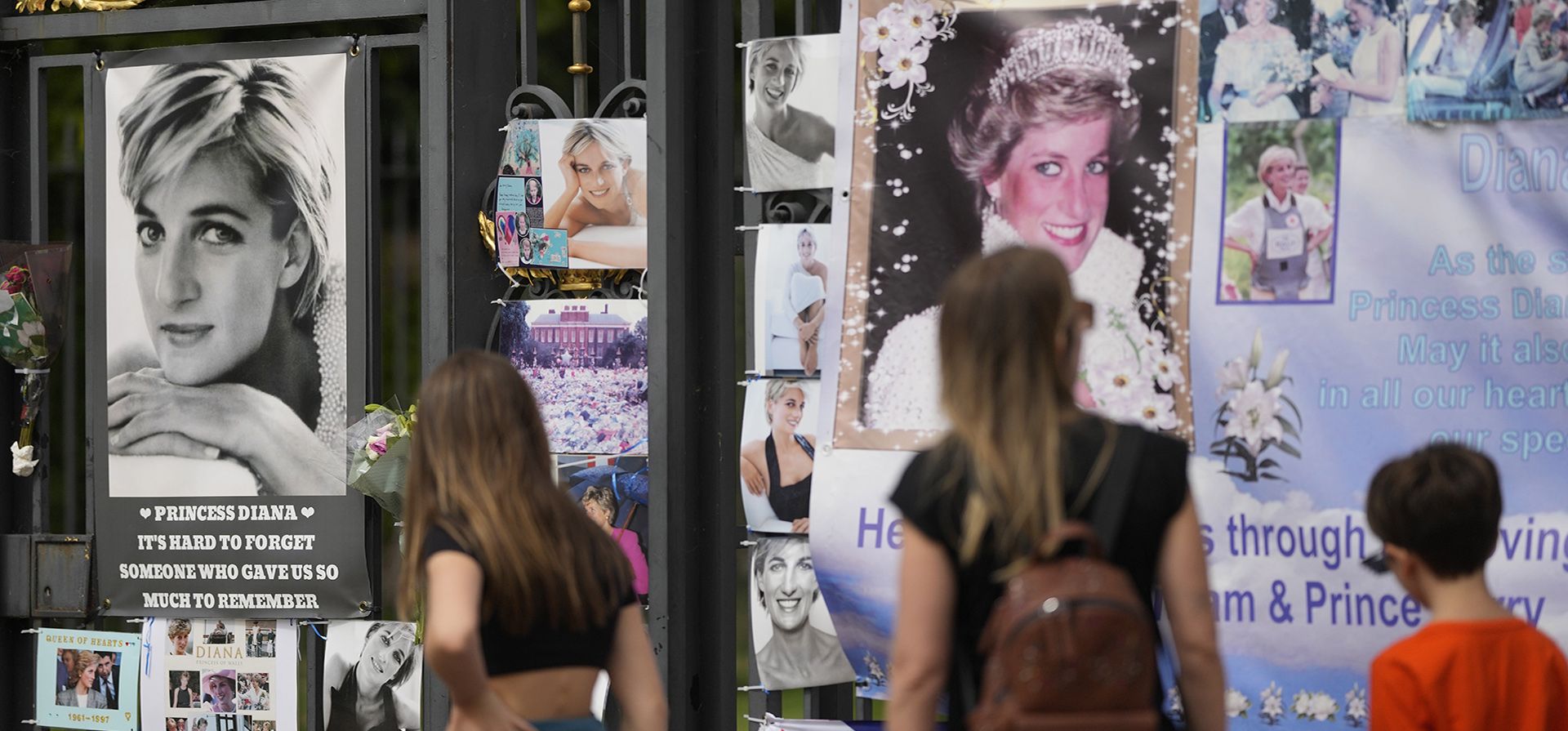 La gente pasa caminando y ve retratos de la princesa Diana y otros recuerdos expuestos en las puertas del Palacio de Kensington, en Londres, el martes 30 de agosto de 2022. Esta semana se cumple el 25 aniversario de la muerte de la princesa Diana en un accidente automovilístico en París.
