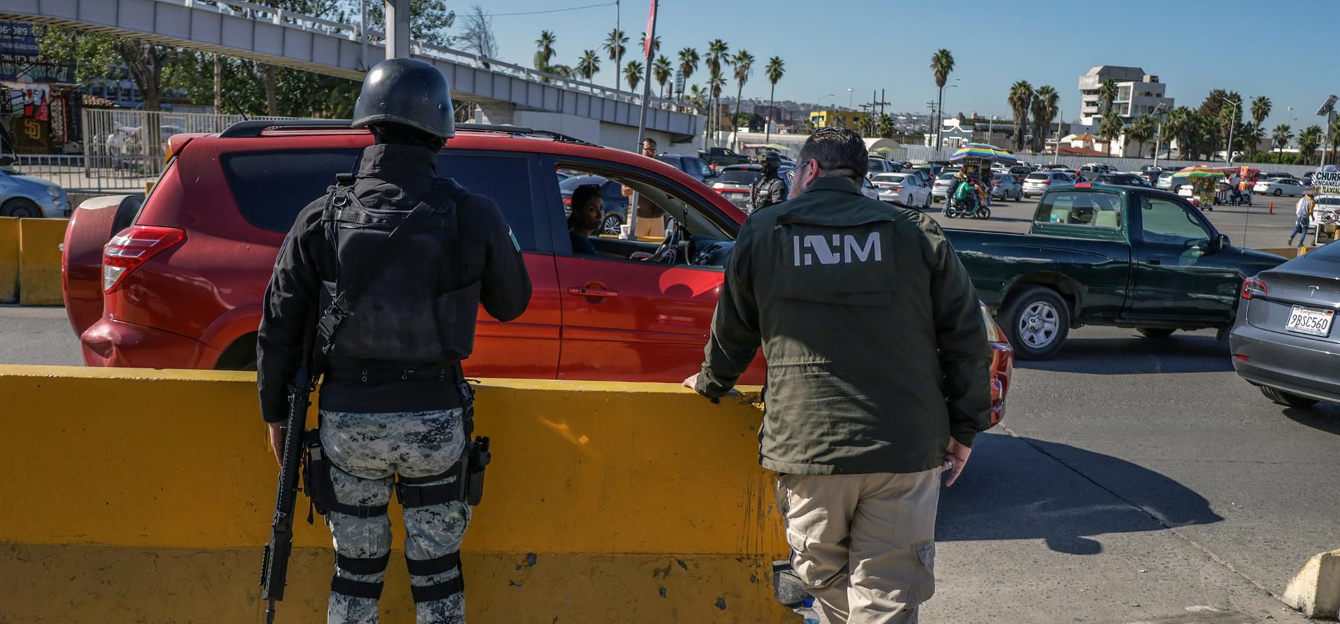 Integrantes del Instituto Nacional de Migración (INM) y de la Guardia Nacional (GN) vigilan vehículos que hacen fila hoy, para cruzar la frontera hacia Estados Unidos por la garita de San Isidro en Tijuana, Baja California (México). Un nuevo punto de revisión en la frontera de Tijuana con Estados Unidos, causó este miércoles polémica entre los usuarios, quienes lo perciben como un plan para detener migrantes que no resolverá los problemas de tránsito vehicular. EFE/Joebeth Terríquez