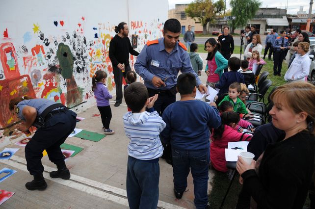 Agentes de la Policía Comunitaria junto a chicos y vecinos realizando el mural.
