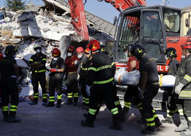 Penoso. Bomberos trasladan los restos de una mujer que sucumbió a los derrumbes en la ciudad medieval de Amatrice.