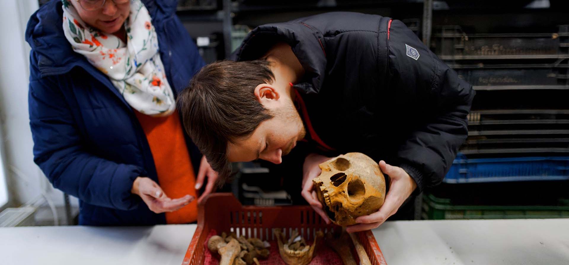 Los arqueólogos húngaros Gabriella Fenyes y Gergely Kostyal examinan el cráneo de una mujer de la época romana tras el hallazgo de sus restos el miércoles 19 de noviembre de 2025 en Budapest, Hungría. (Foto AP/Bela Szandelszky)
