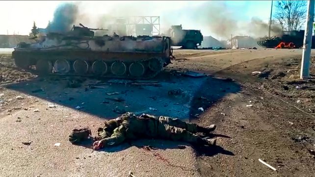 Captura de un video publicado por el Servicio de Prensa del Departamento de Policía de Ucrania, el cuerpo de un soldado muerto yace en el suelo junto a vehículos militares destrozados después de un ataque en el este de Ucrania. (Servicio de Prensa del Departamento de Policía de Ucrania vía AP)