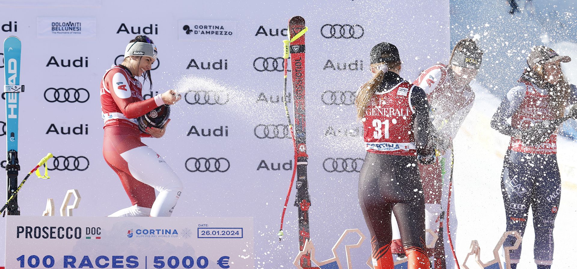 La austriaca Stephanie Venier (izquierda), ganadora de una carrera de descenso de la Copa Mundial femenina de esquí alpino, celebra en el podio con la canadiense Valerie Grenier, tercera desde la derecha, la austriaca Christina Ager, segunda desde la derecha, y la italiana Sofia Goggia, a la derecha, que empató en el tercer puesto. Lugar, en Cortina d