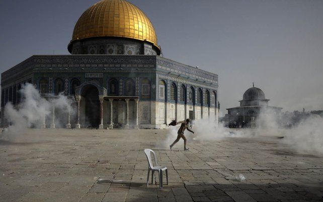 Un palestino huye de los gases lacrimógenos durante los enfrentamientos con las fuerzas de seguridad israelíes frente a la Mezquita de la Cúpula de la Roca en el recinto de la Mezquita Al Aqsa en la Ciudad Vieja de Jerusalén.